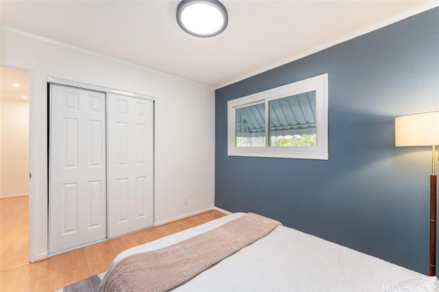 bedroom featuring a closet, crown molding, baseboards, and wood finished floors