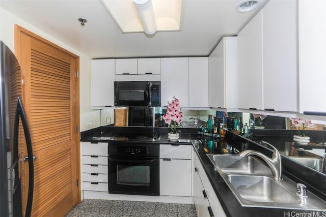 kitchen with black appliances, dark countertops, a sink, and white cabinets