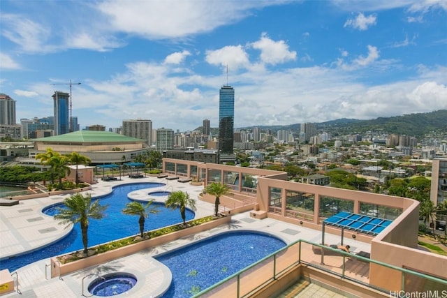 pool featuring a community hot tub, a patio area, and a city view