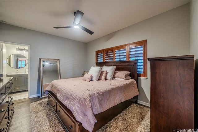 bedroom with ceiling fan, ensuite bathroom, a sink, wood finished floors, and baseboards