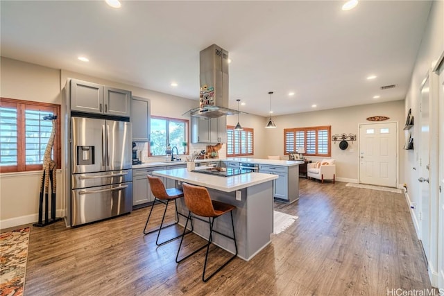 kitchen featuring a breakfast bar area, a kitchen island, light countertops, stainless steel fridge, and pendant lighting