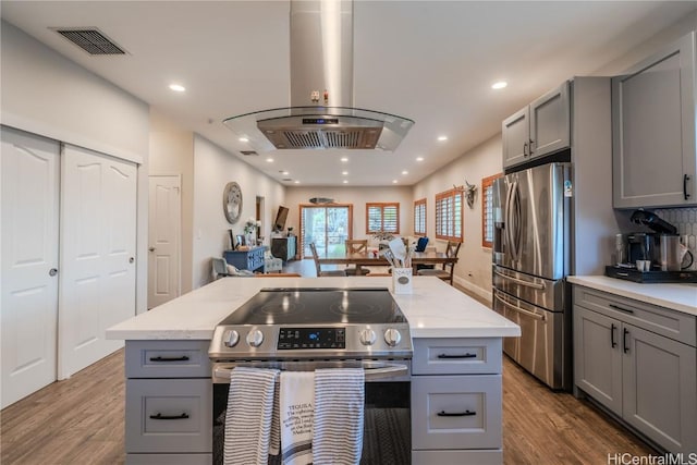 kitchen featuring visible vents, appliances with stainless steel finishes, wood finished floors, island exhaust hood, and gray cabinetry