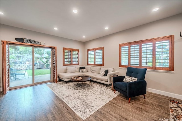 living area with baseboards, wood finished floors, and recessed lighting