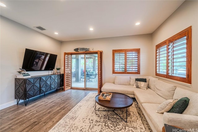 living area with recessed lighting, visible vents, baseboards, and wood finished floors