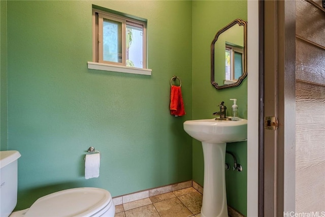 bathroom with baseboards, toilet, and tile patterned floors