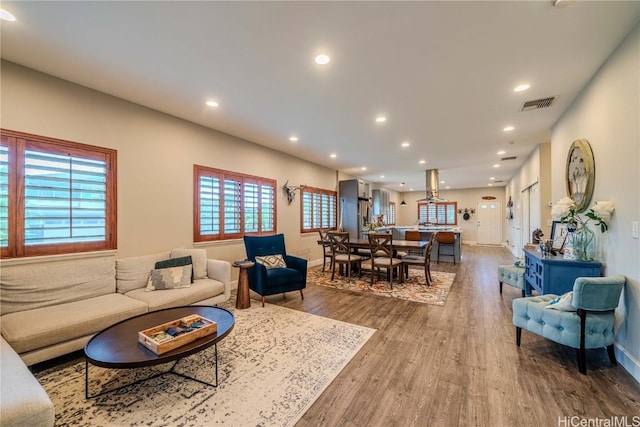 living room with recessed lighting, visible vents, baseboards, and wood finished floors