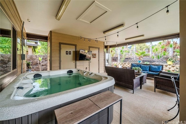 exterior space with a wealth of natural light, rail lighting, and a jacuzzi