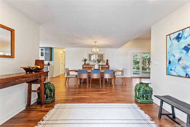 dining space featuring baseboards, an inviting chandelier, and wood finished floors