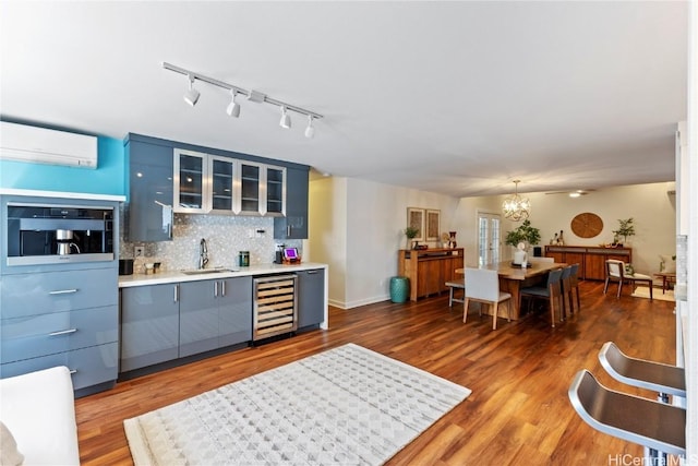 kitchen with light wood finished floors, tasteful backsplash, a sink, beverage cooler, and a wall mounted air conditioner