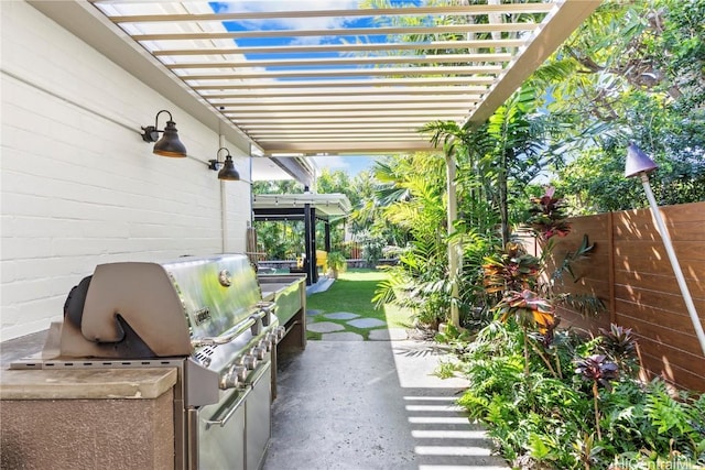 view of patio with an outdoor kitchen, grilling area, fence, and a pergola