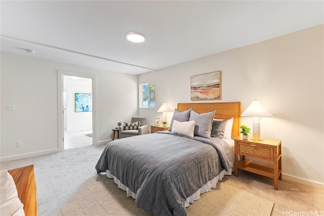 bedroom featuring light colored carpet, baseboards, and ensuite bathroom