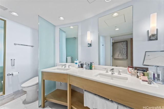 bathroom featuring toilet, double vanity, visible vents, and a sink