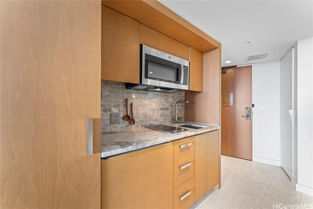 kitchen with light tile patterned flooring, a sink, visible vents, light countertops, and stainless steel microwave