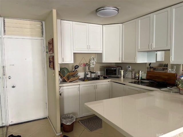 kitchen with light countertops, a toaster, white cabinetry, and light tile patterned floors