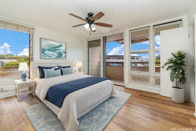 bedroom featuring access to outside, expansive windows, a ceiling fan, and wood finished floors