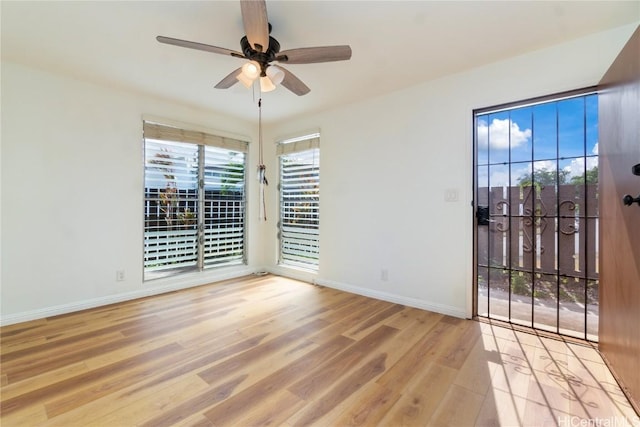 spare room with plenty of natural light, light wood-style flooring, baseboards, and a ceiling fan