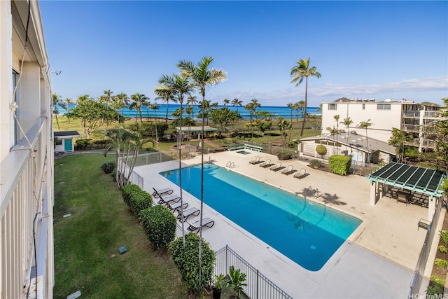 community pool featuring a water view, a patio, fence, and a lawn