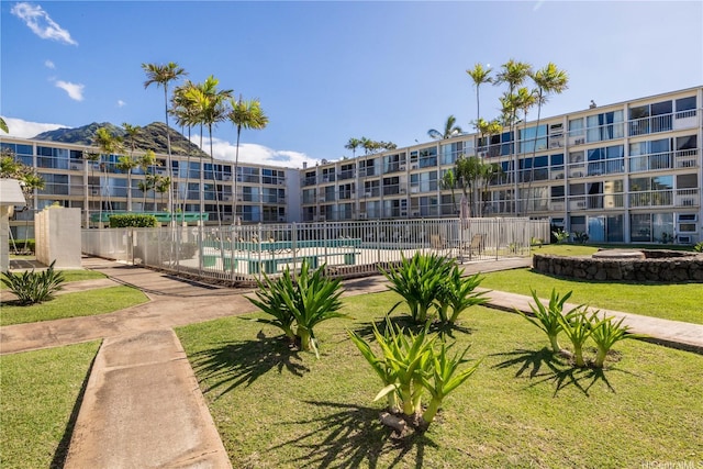 surrounding community with a lawn, a pool, and fence
