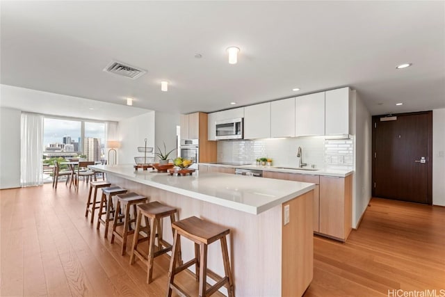 kitchen featuring white cabinets, a center island, stainless steel appliances, light countertops, and a sink