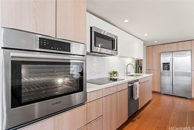 kitchen featuring a sink, light countertops, appliances with stainless steel finishes, light brown cabinetry, and modern cabinets