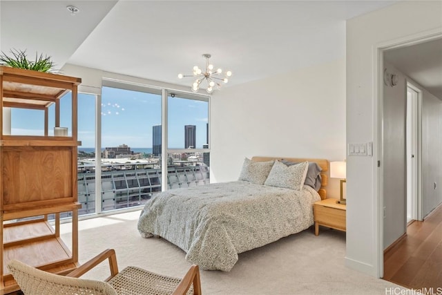 bedroom featuring access to outside, wood finished floors, a city view, and an inviting chandelier