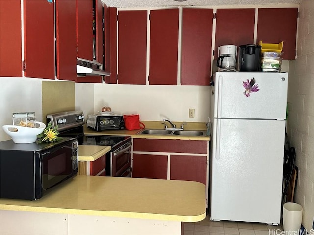 kitchen with black microwave, a sink, red cabinets, freestanding refrigerator, and stainless steel electric stove