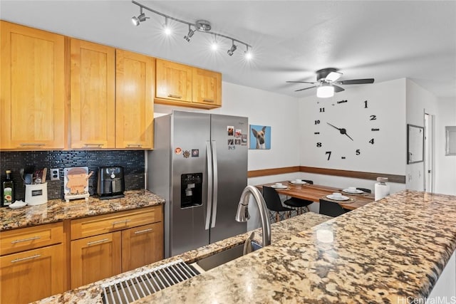 kitchen with light stone counters, tasteful backsplash, a ceiling fan, and stainless steel fridge with ice dispenser