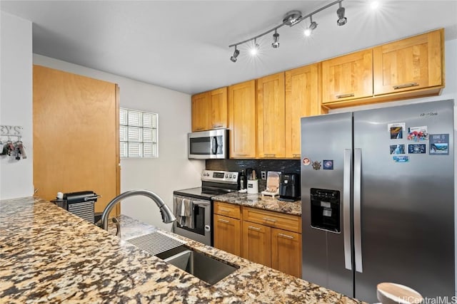 kitchen with dark stone countertops, decorative backsplash, stainless steel appliances, and a sink