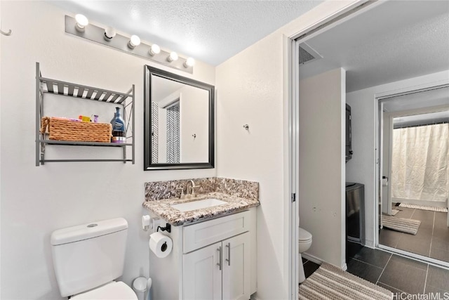 bathroom with tile patterned floors, a textured ceiling, toilet, and vanity