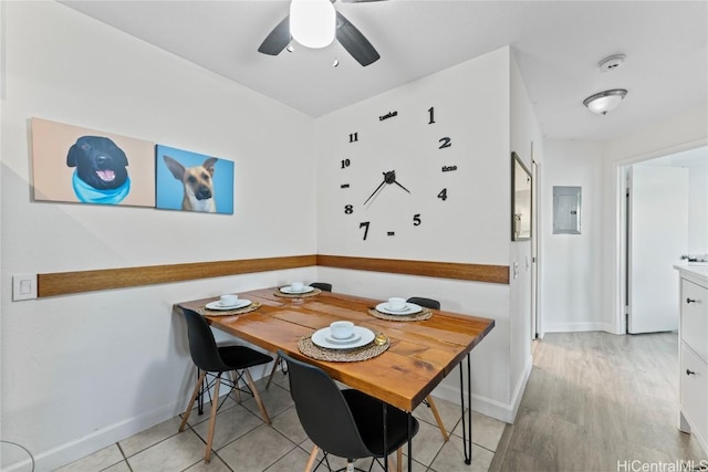 dining room featuring light wood-style floors, electric panel, baseboards, and a ceiling fan