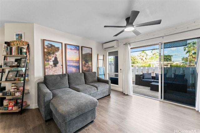 living room with a wall unit AC, a ceiling fan, and wood finished floors