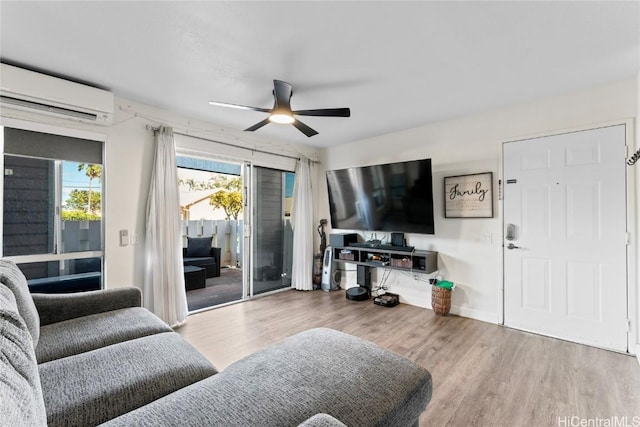 living area featuring a wall unit AC, baseboards, a ceiling fan, and wood finished floors