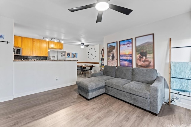 living room with baseboards, a ceiling fan, and wood finished floors