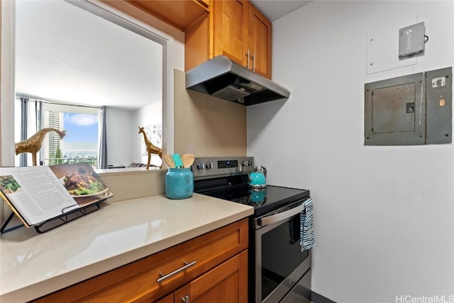 kitchen with under cabinet range hood, electric stove, light countertops, electric panel, and brown cabinets