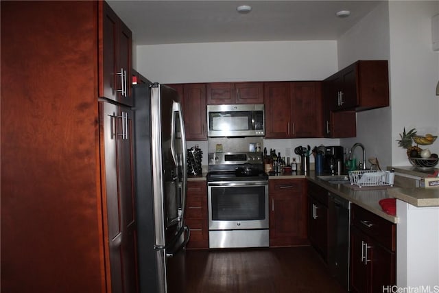 kitchen with appliances with stainless steel finishes, light countertops, dark wood-type flooring, and a sink