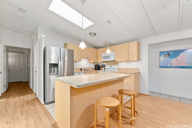 kitchen with white appliances, a kitchen island, light wood-style floors, and light brown cabinetry