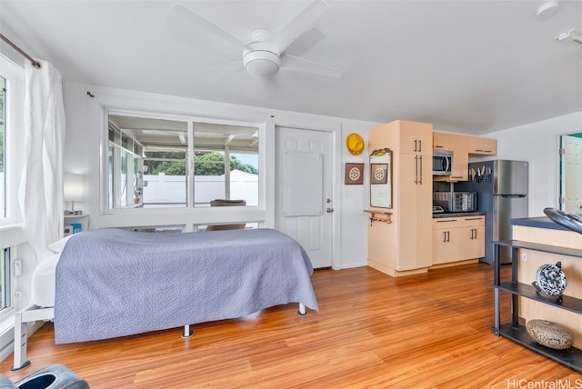 bedroom featuring light wood finished floors, freestanding refrigerator, and a ceiling fan