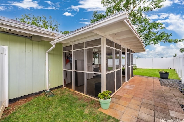 exterior space featuring a sunroom, a fenced backyard, a patio area, and a lawn