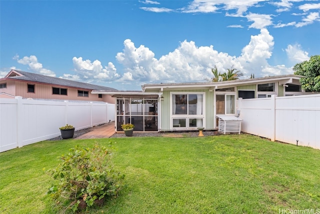 rear view of property featuring a sunroom, a fenced backyard, and a yard