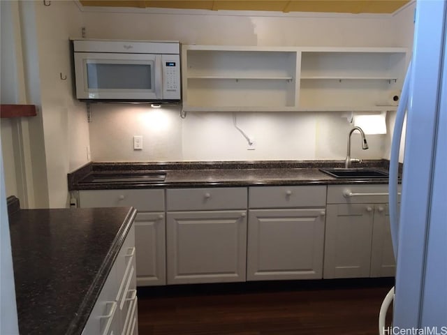 kitchen featuring white cabinets, dark wood finished floors, white microwave, open shelves, and a sink