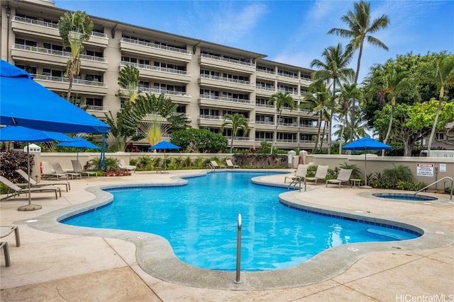 community pool featuring a patio area, fence, and a hot tub