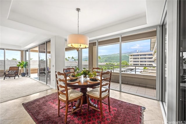 dining area featuring light tile patterned floors, a raised ceiling, and a healthy amount of sunlight