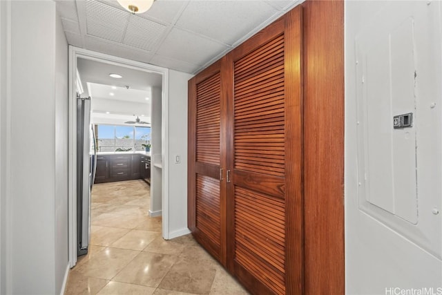 hall featuring light tile patterned floors, electric panel, and baseboards