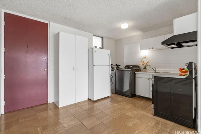 kitchen featuring light countertops, freestanding refrigerator, washer / clothes dryer, and white cabinetry