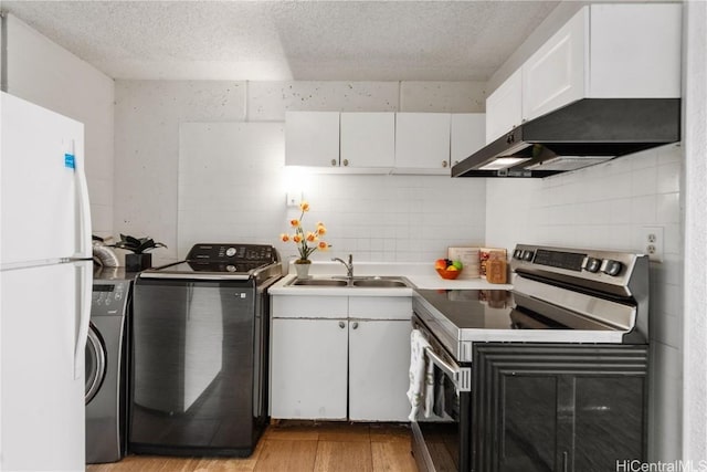 kitchen featuring freestanding refrigerator, electric range, a sink, and washer / dryer