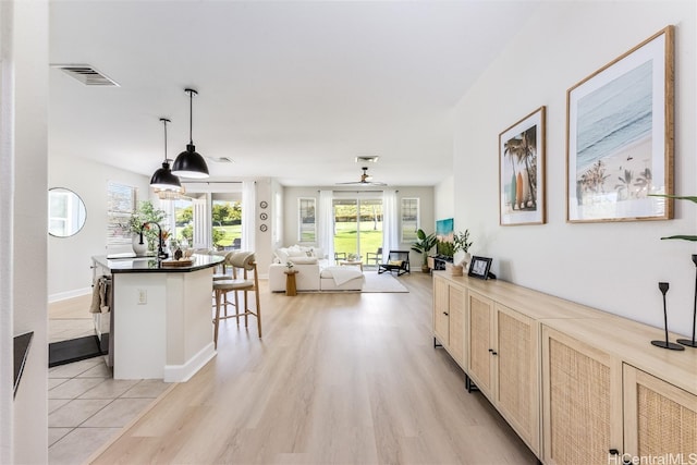 kitchen featuring light brown cabinets, a sink, visible vents, a kitchen breakfast bar, and light wood-type flooring