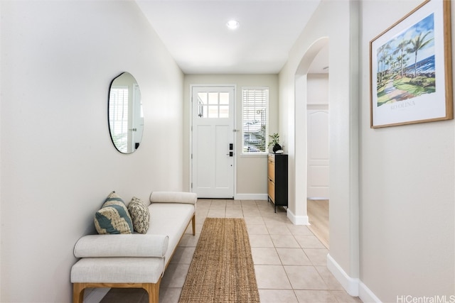 entryway featuring light tile patterned floors, baseboards, and arched walkways