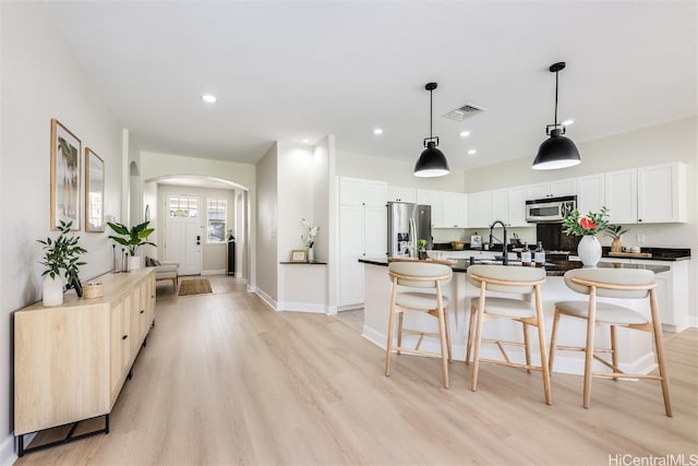 kitchen with arched walkways, appliances with stainless steel finishes, dark countertops, and visible vents