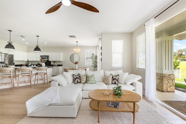 living room featuring light wood finished floors, visible vents, and a ceiling fan