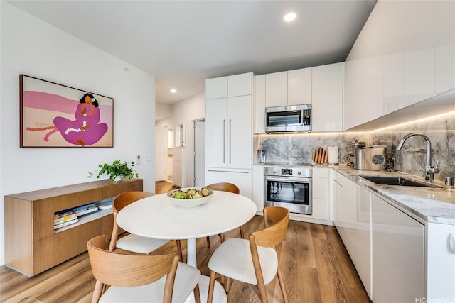 987 Queen St Unit 502, Honolulu, HI 96814 - kitchen with appliances with stainless steel finishes, a sink, light wood-style flooring, white cabinetry, and recessed lighting